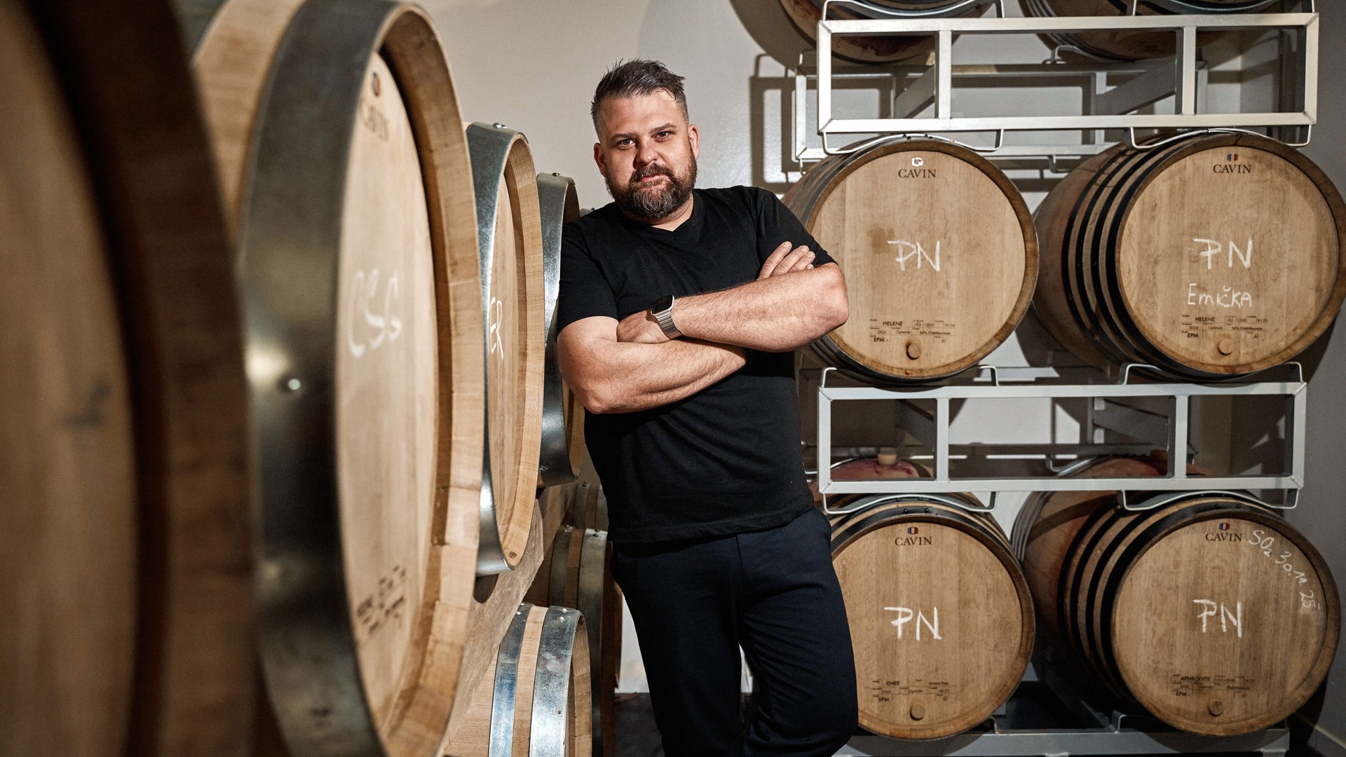 Karel Novotný surrounded by barrels in his wine cellar